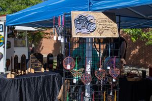 Row of vendor tents with merchandise displays under blue canopies at street fair.