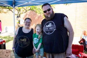 Vendor booth with displays and canopy tent at outdoor community market event.