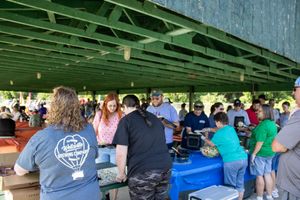 Large crowd gathered under a covered outdoor pavilion at a community event.