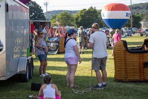 Summer festival scene with food vendors and attendees enjoying outdoor activities.