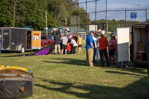 Outdoor festival with vendor tents and attendees spread across a grassy field.