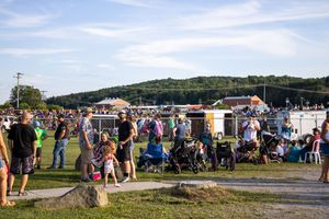 Wide view of a festival venue showing food trucks, tents, and crowds on a sunny afternoon.