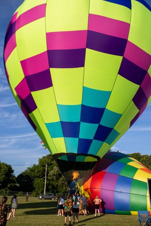 Vibrant hot air balloon with neon yellow, pink, and blue geometric patterns against a bright blue sky.