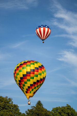 Colorful hot air balloons ascending in sequence against vibrant blue sky.