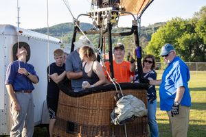 Hot air balloon crew members preparing basket and equipment for flight.