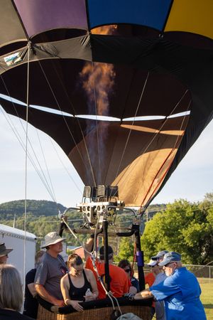Hot air balloon crews prepare colorful balloons for flight at an outdoor festival on a grassy field.