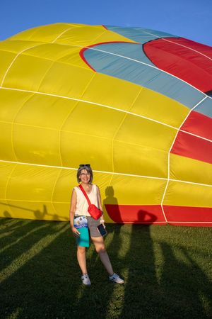 Deflated hot air balloon envelope laying on grass casting long shadows.