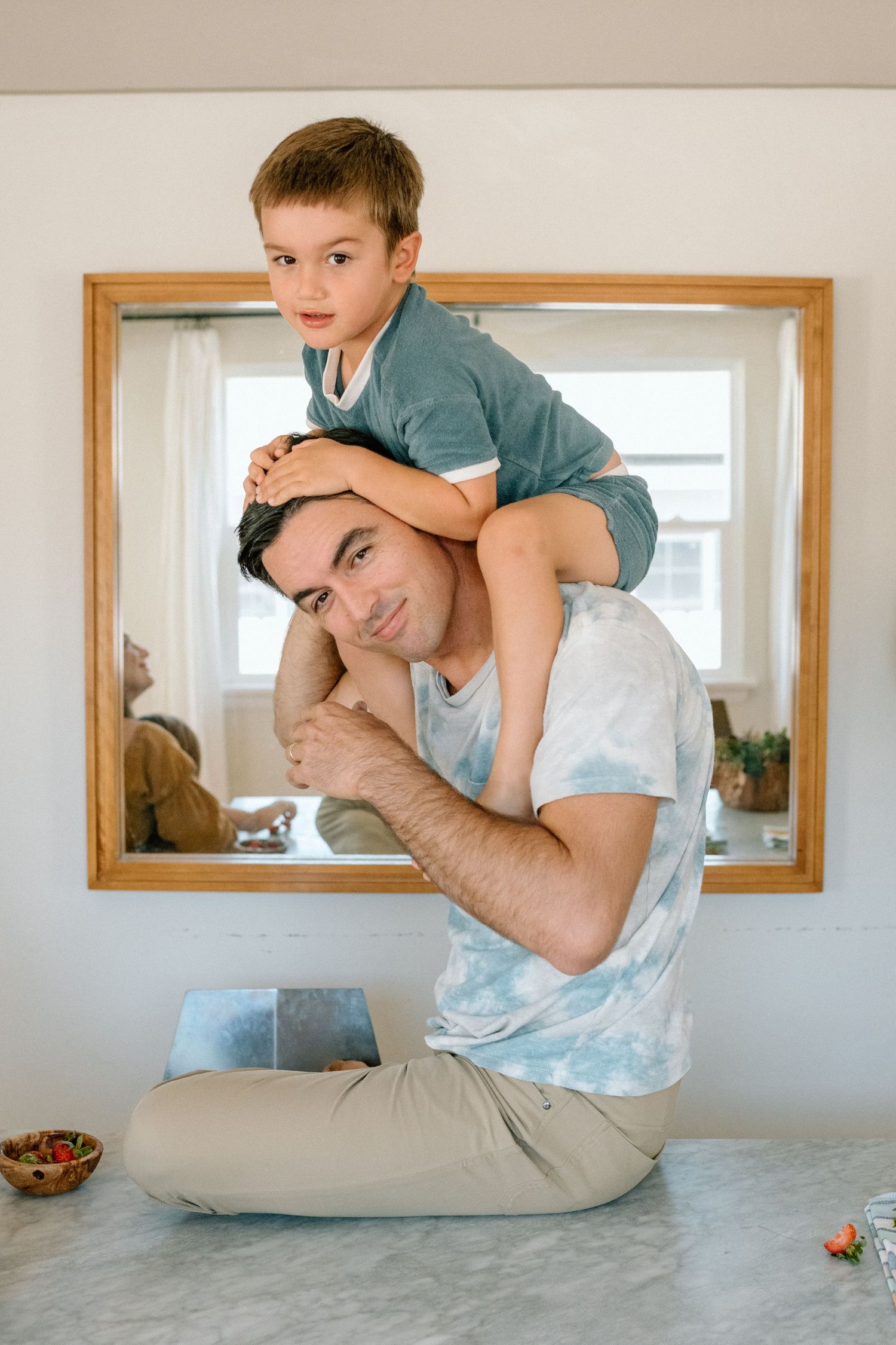 A playful parent and child share a tender moment as they play together on the floor near a wall mirror.