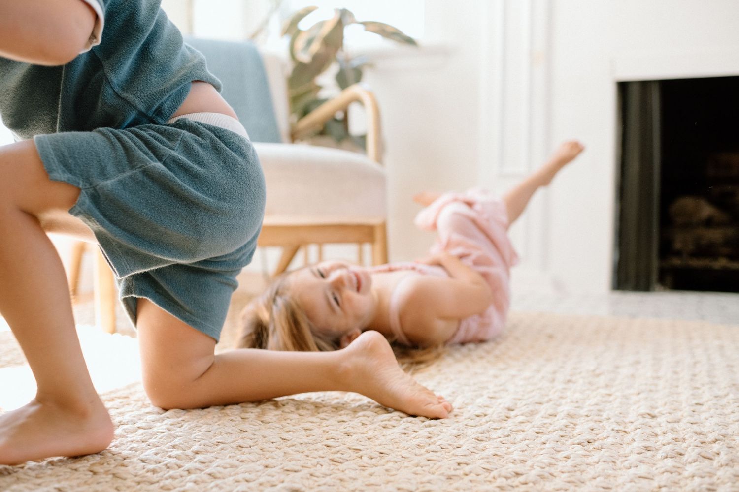 Baby in blue outfit crawls across textured beige carpet in bright sunny room.