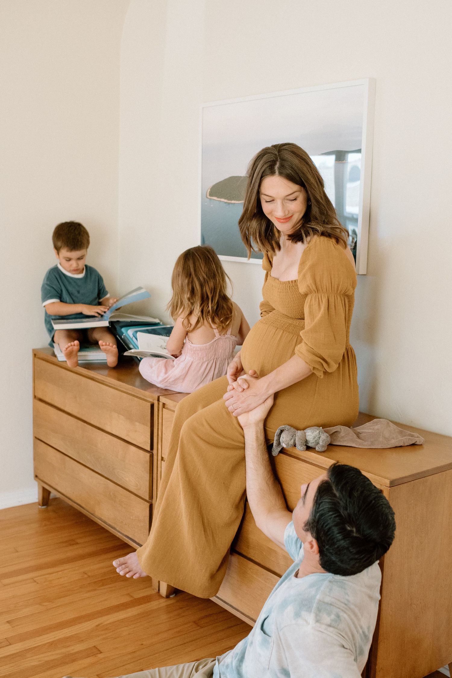 Family spending quality time together in bedroom while using digital devices on wooden dresser.