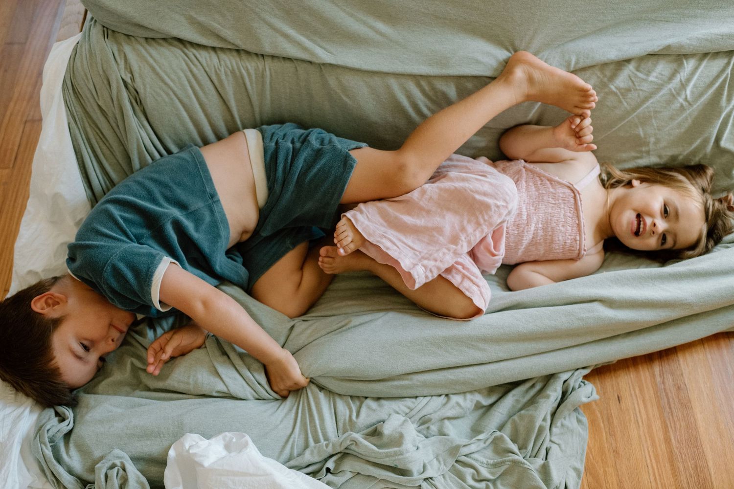 Artistic photo series showing a person in relaxed poses laying on neutral bedding in morning light.