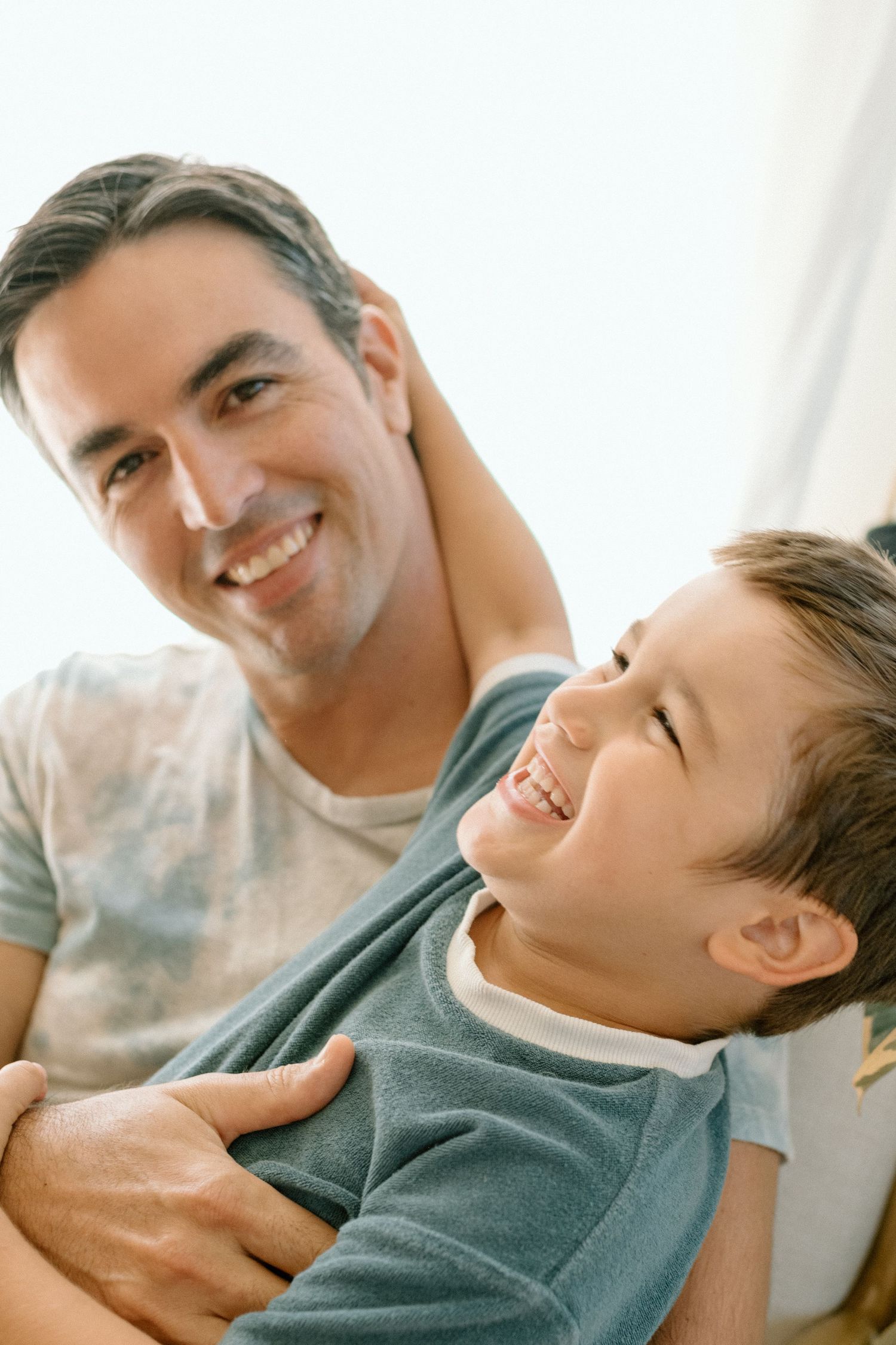 A candid moment of shared joy and laughter between parent and child in natural lighting.