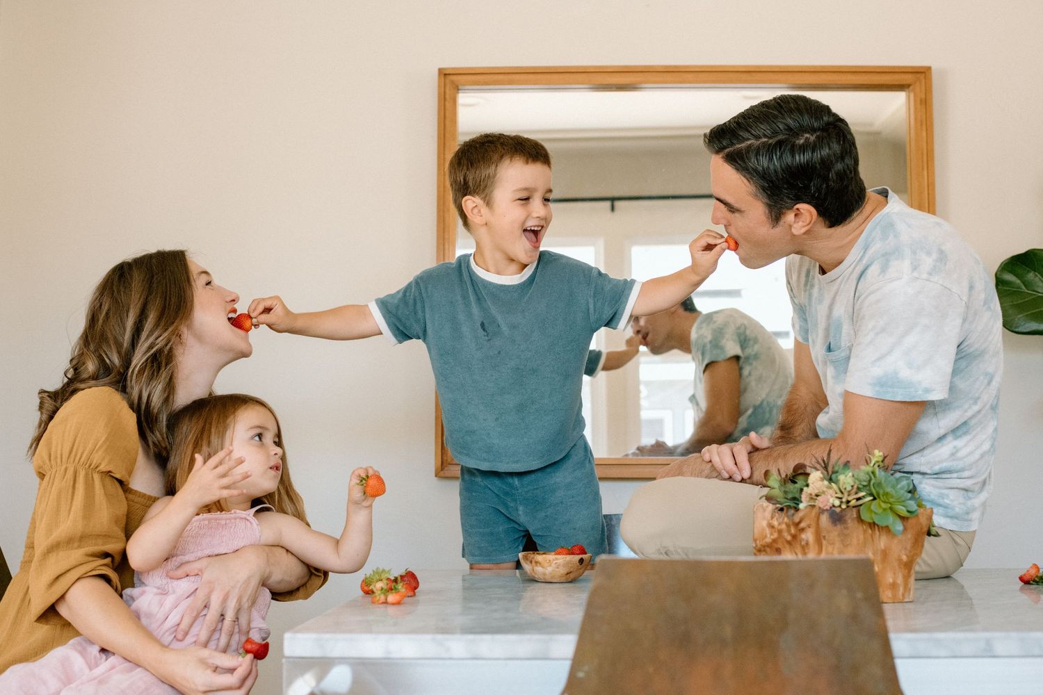 Family sharing laughs and having fun while feeding each other sushi rolls in bright kitchen setting.