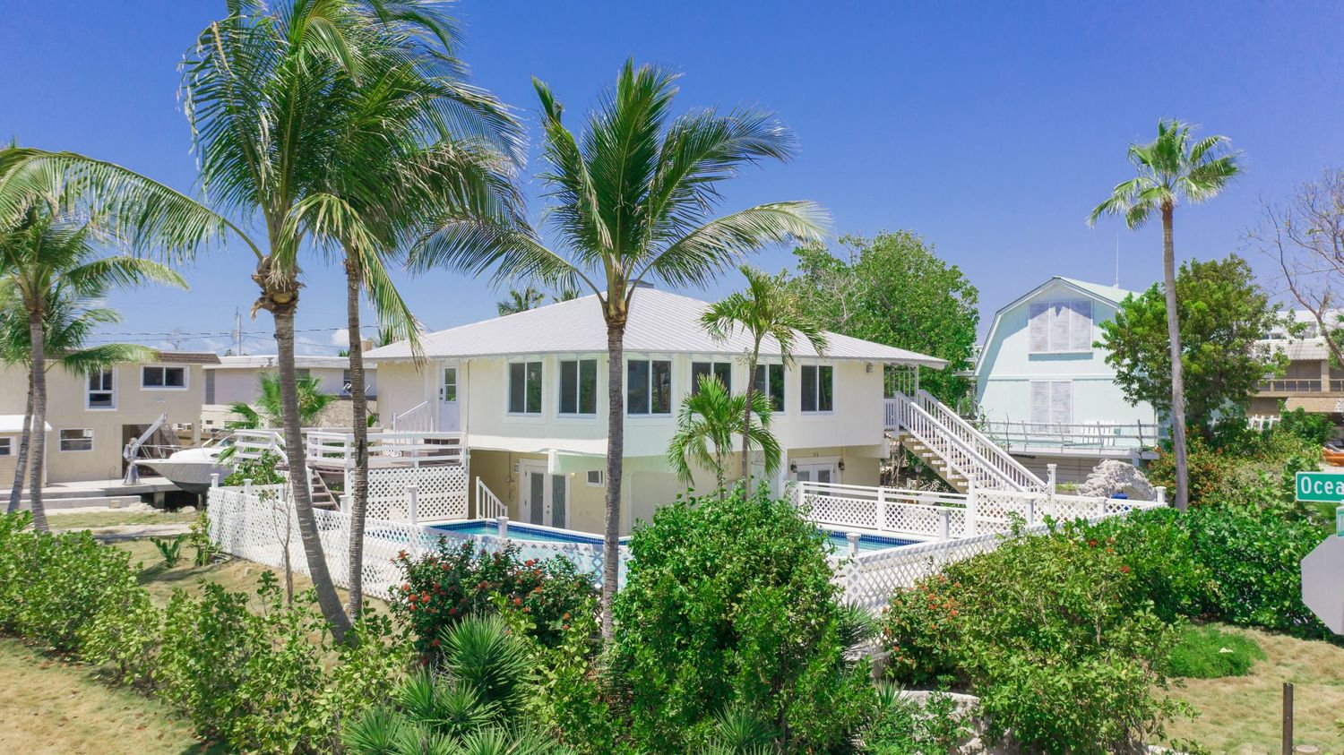 Aerial panorama of waterfront homes with palm trees and pools along a coastal residential community.