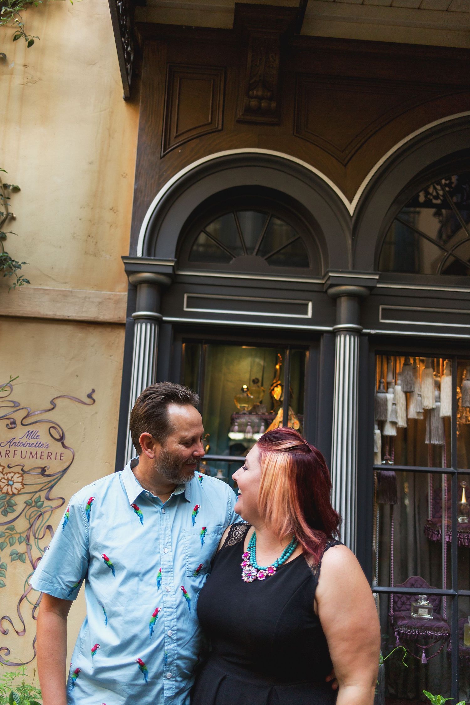 Candid engagement session outside a vintage storefront with arched windows.