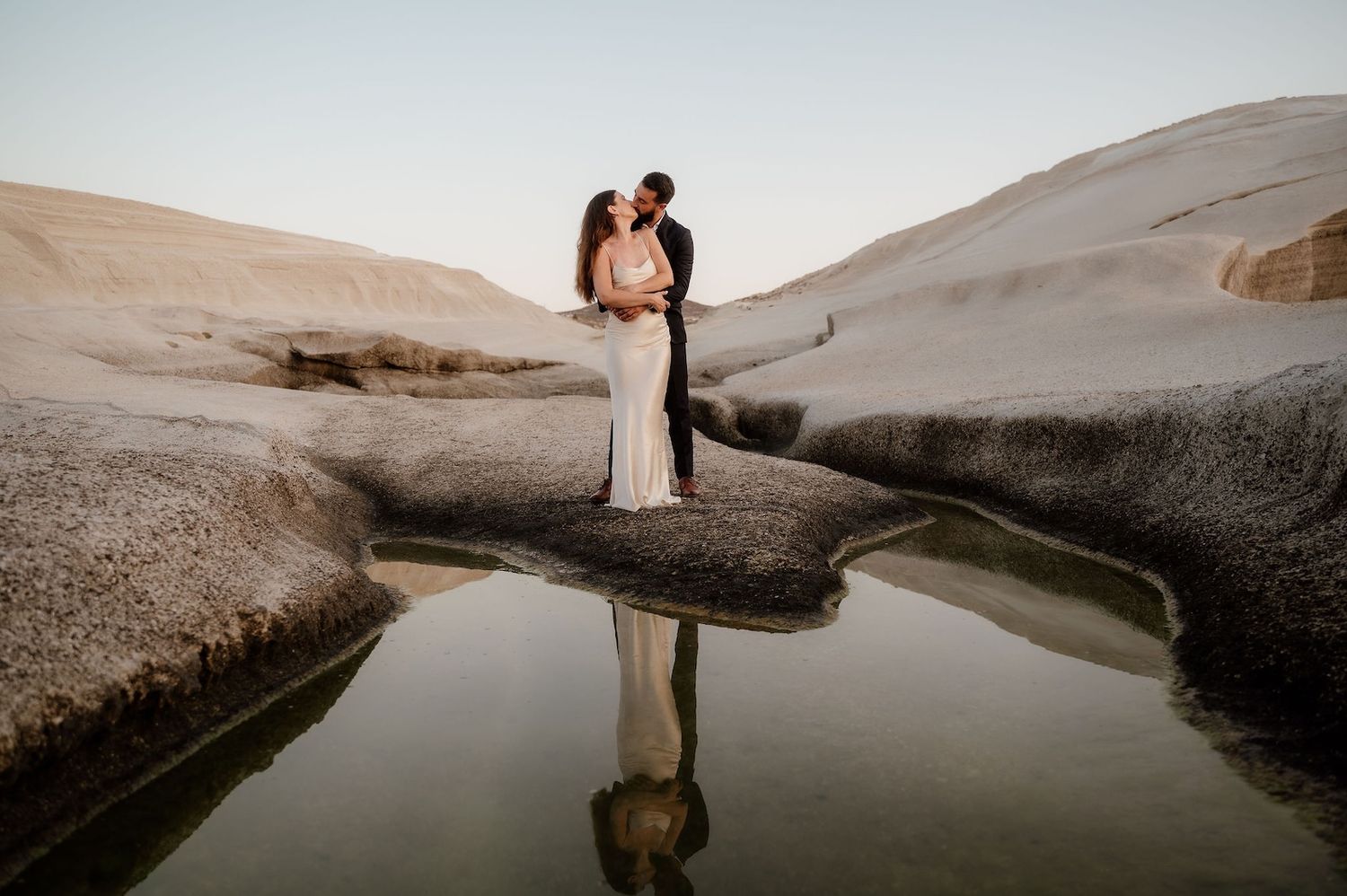 A cinematic photo of a couple kissing at their elopement at Sarakiniko beach, Milos Greece
