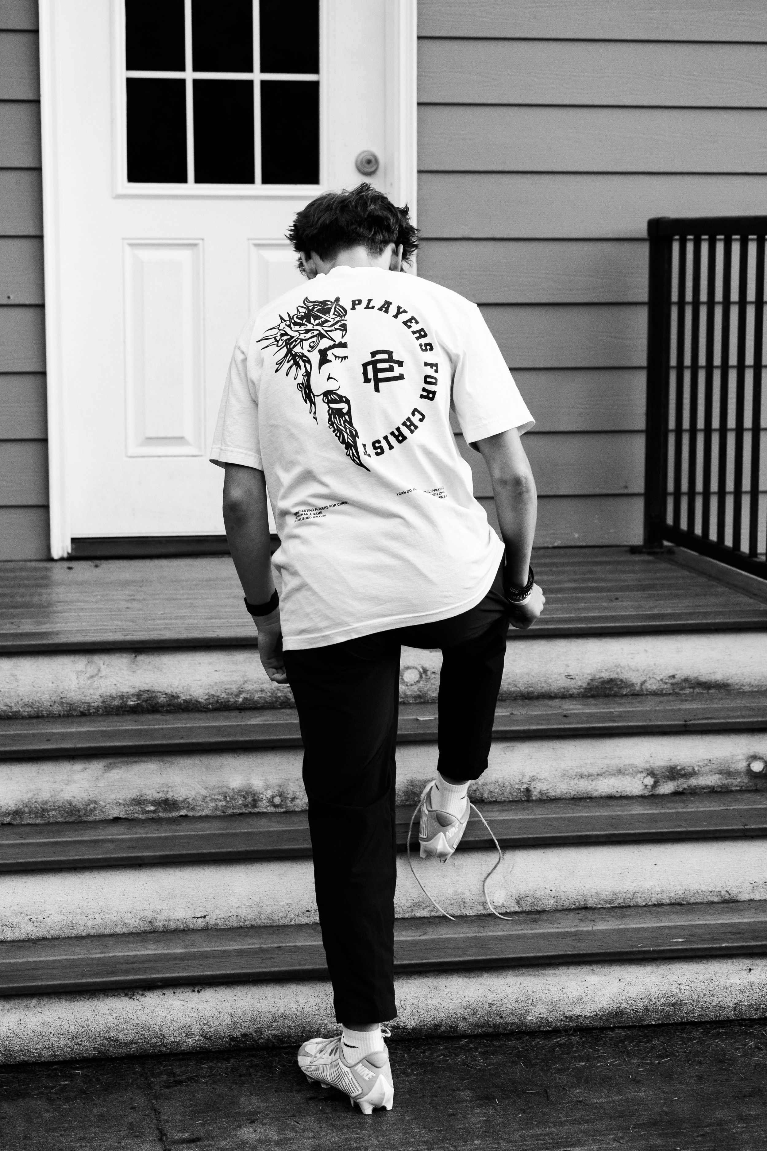 Person wearing Players for Christ t-shirt climbing steps to white door.