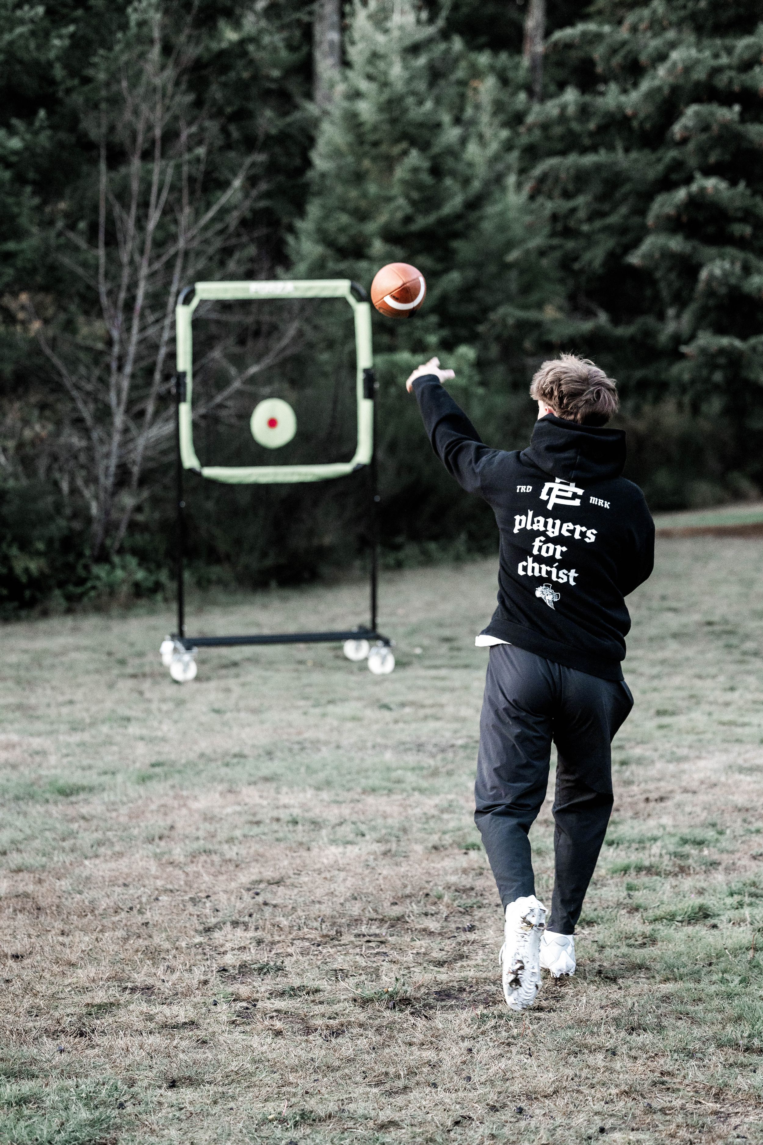 Someone throwing a football at a practice target in an outdoor field.