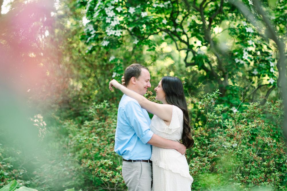 A couple embraces romantically in a dreamy garden setting with soft natural lighting.