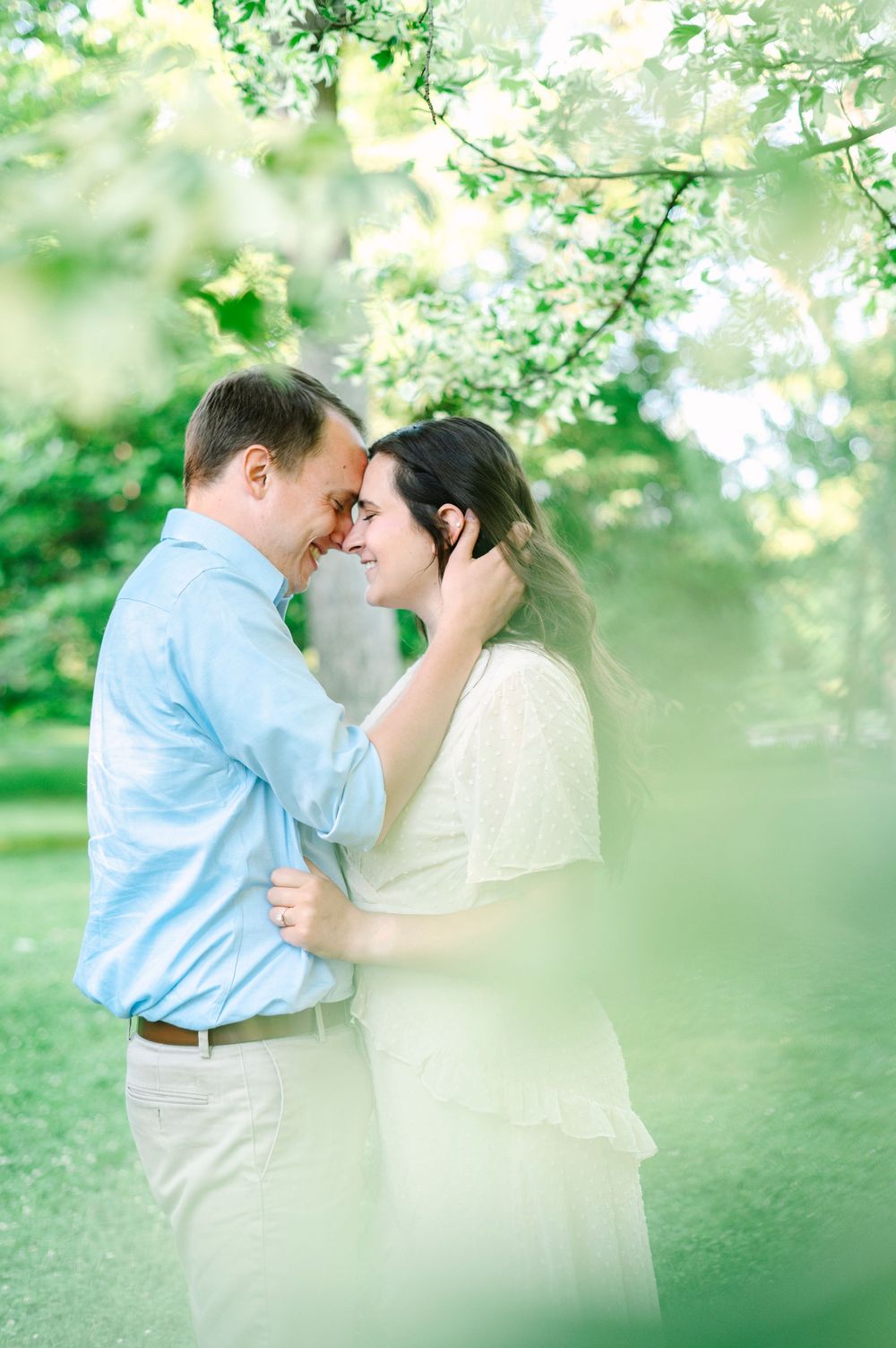 An intimate moment between a couple in a dreamy garden setting with soft focus greenery.