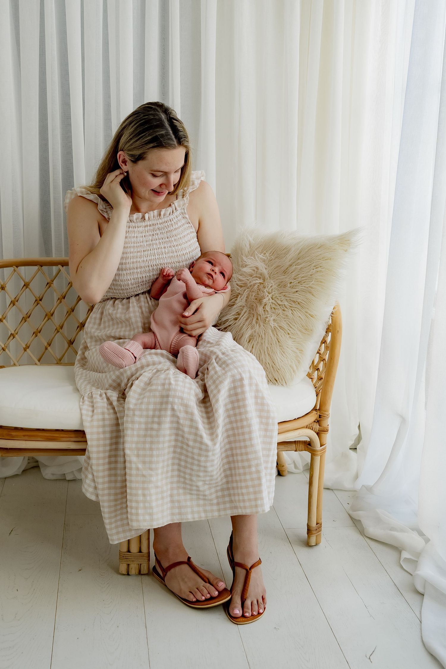 A series of photos showing tender moments between parent and newborn on a woven bamboo chair with white curtains.