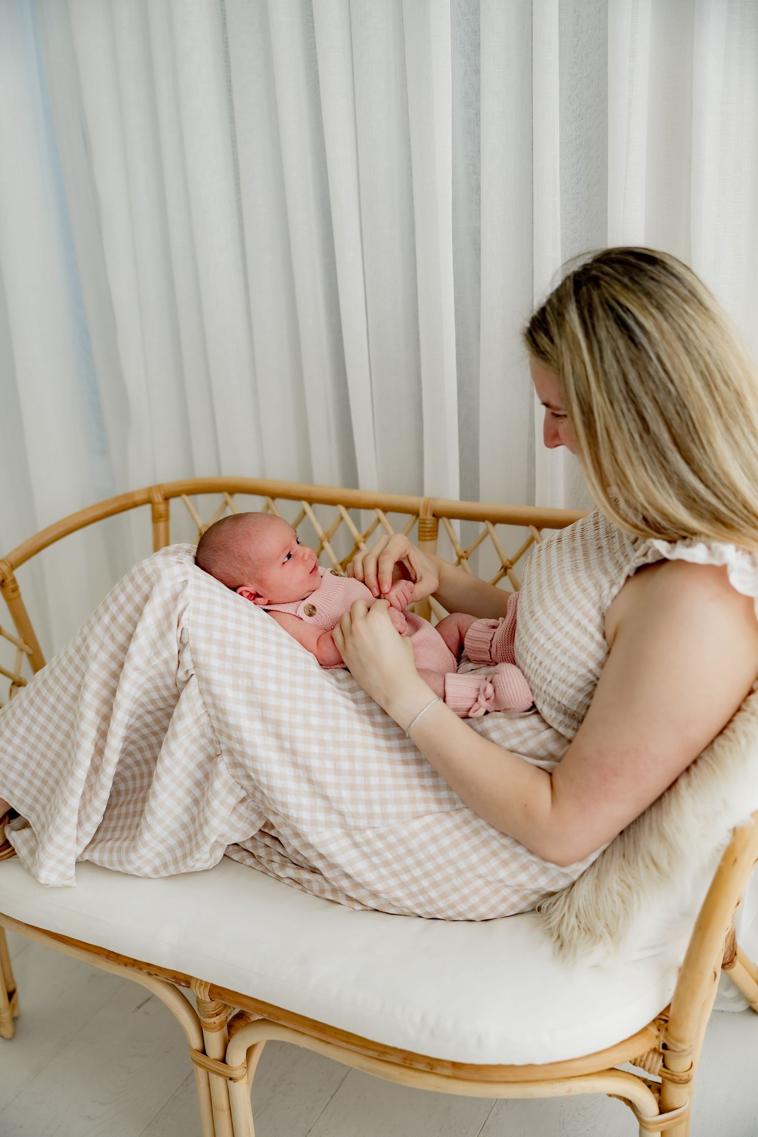 Series of images showing parent and newborn resting together on a bamboo chaise lounge with white cushions.