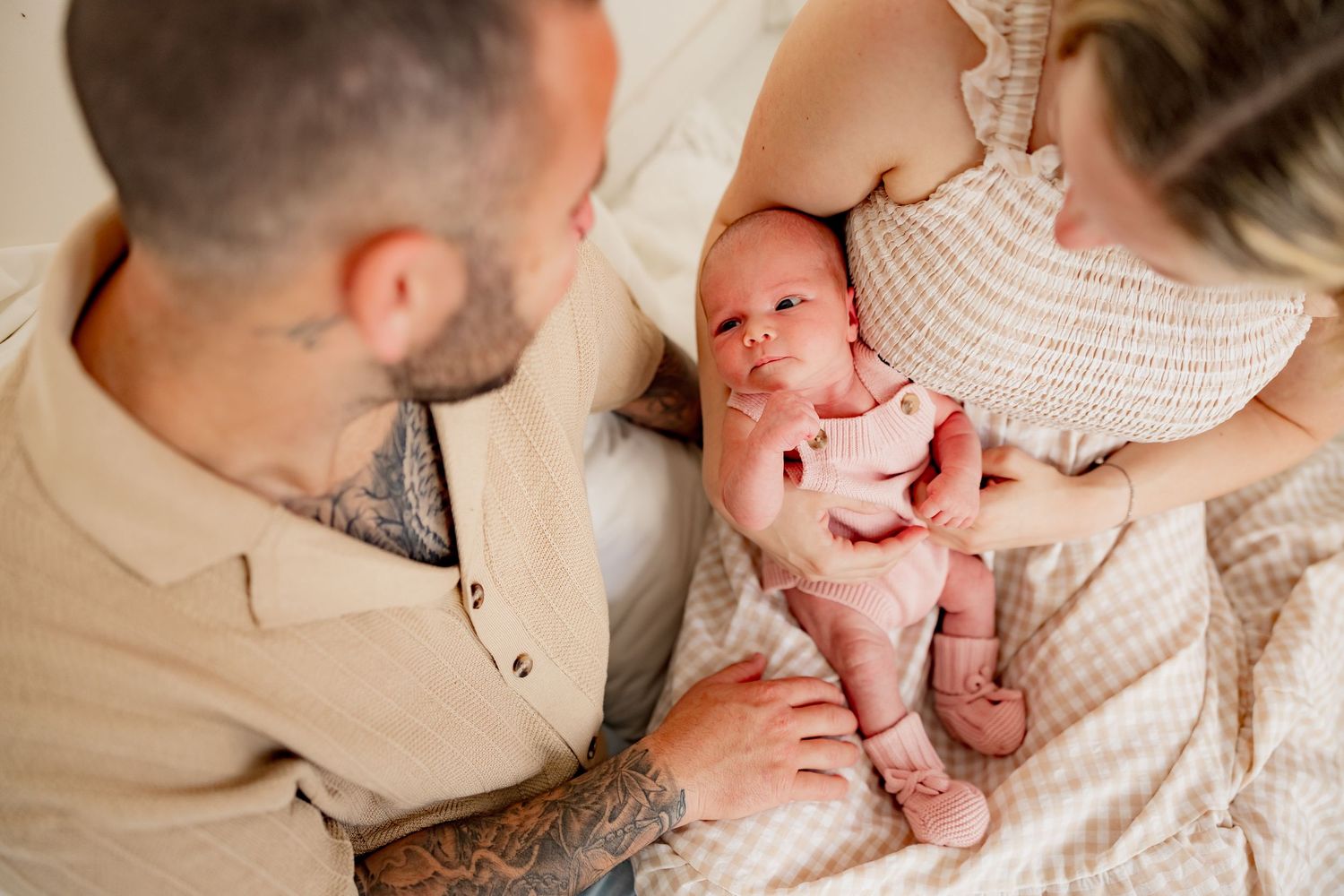 Tender newborn photography session featuring tiny baby feet cradled on soft white blanket.