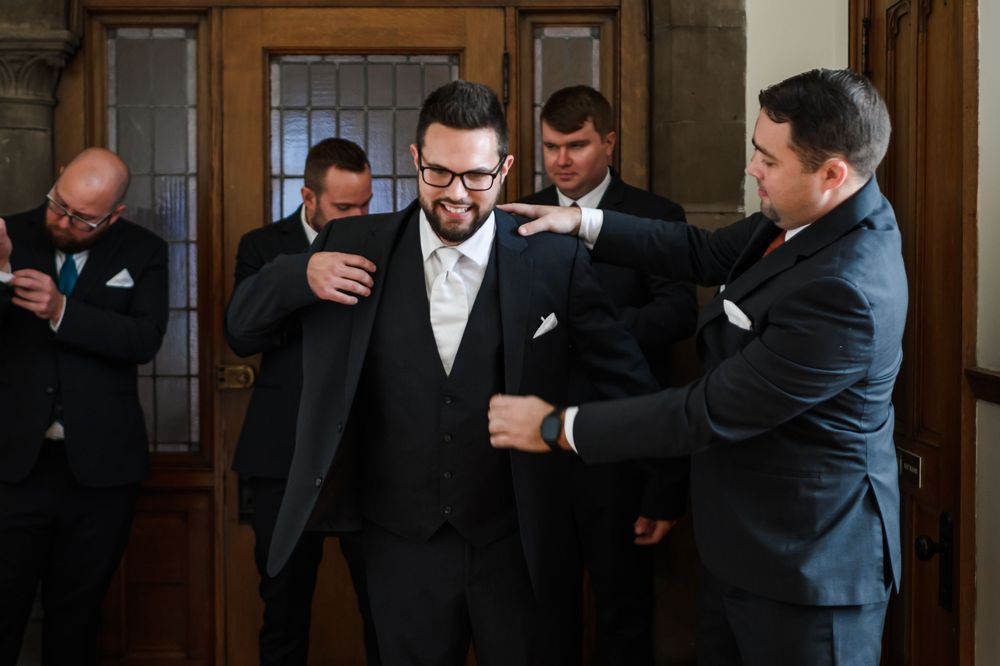 Several men in suits stand in front of wood-paneled walls in what appears to be a formal gathering or event.