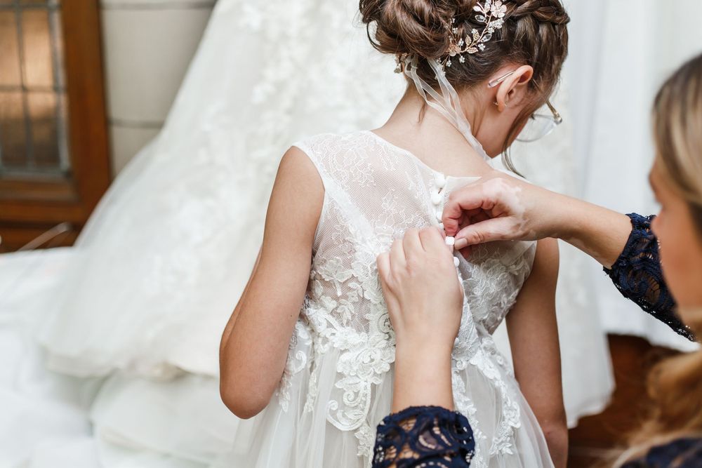 A close-up shot of lace details and floral embellishments on a white wedding dress.