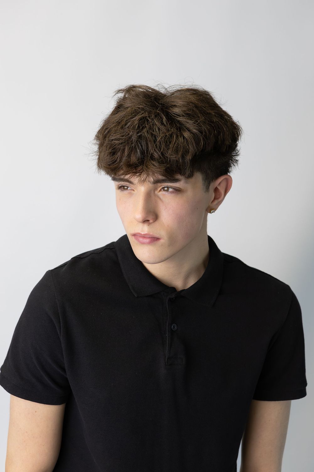 Studio portrait series of young person in black polo shirt against white background.