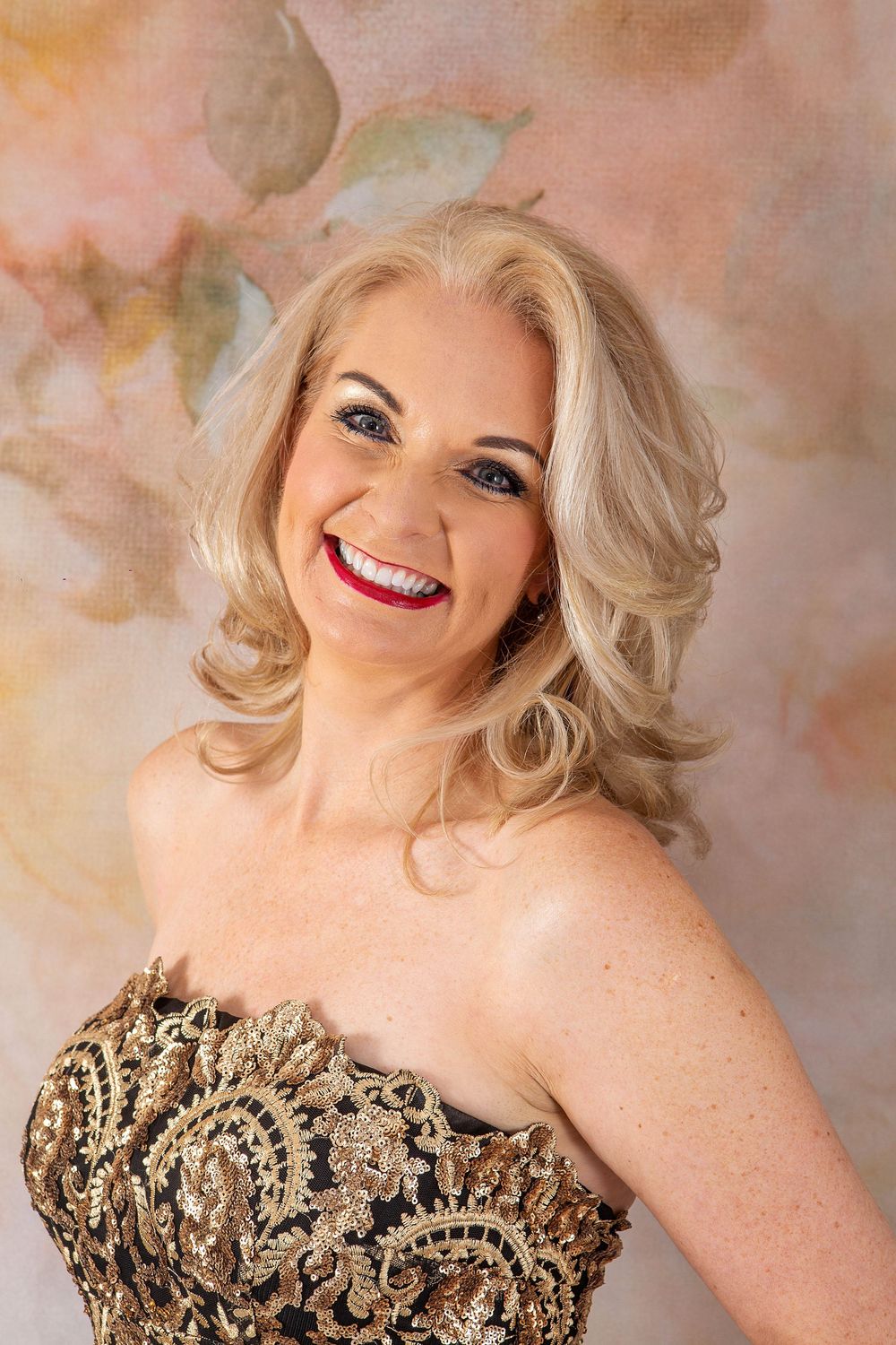 Glamour portrait series featuring woman in sparkly gold dress against peachy backdrop.