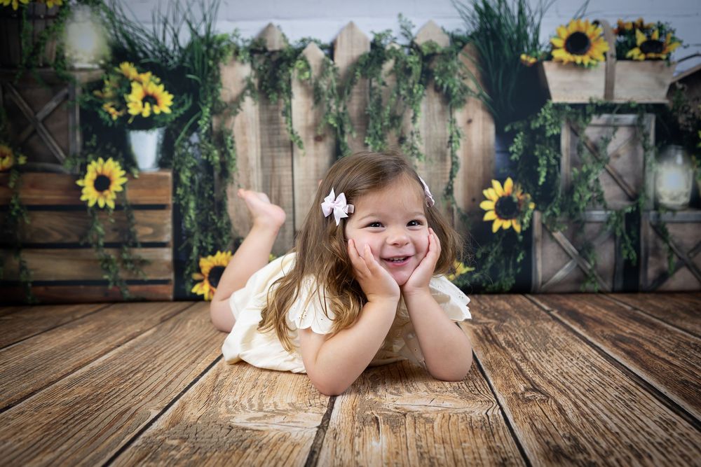 Spring themed child portrait with sunflowers and rustic wooden floor setting.