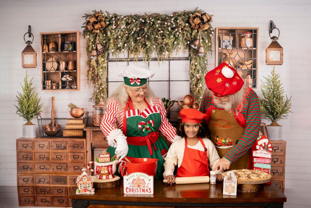 Festive holiday studio setup with rustic wood backdrop, green garland, and Christmas decorations arranged on shelves.