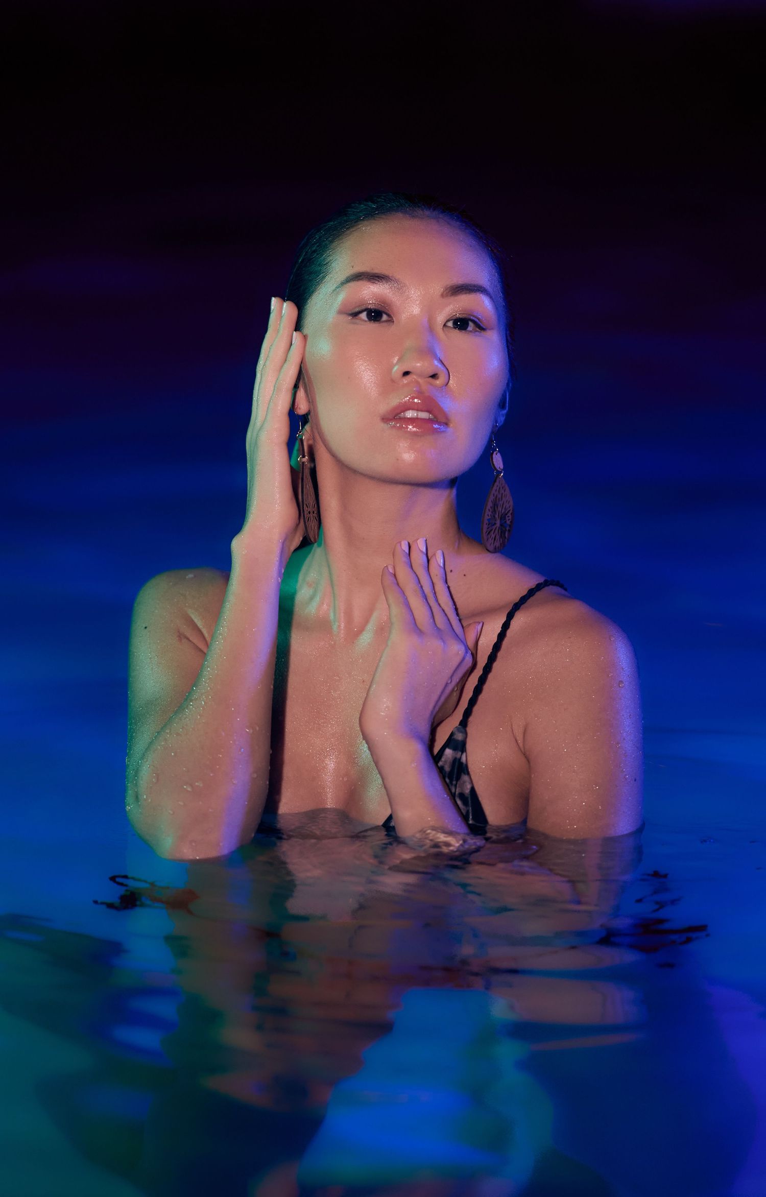 Artistic portrait in dark water with blue lighting creates a moody underwater atmosphere.