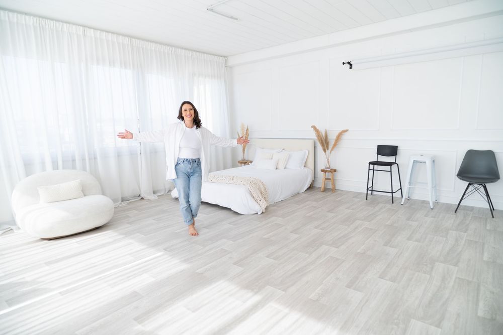 Modern bright white bedroom with minimalist decor and light gray wood flooring.