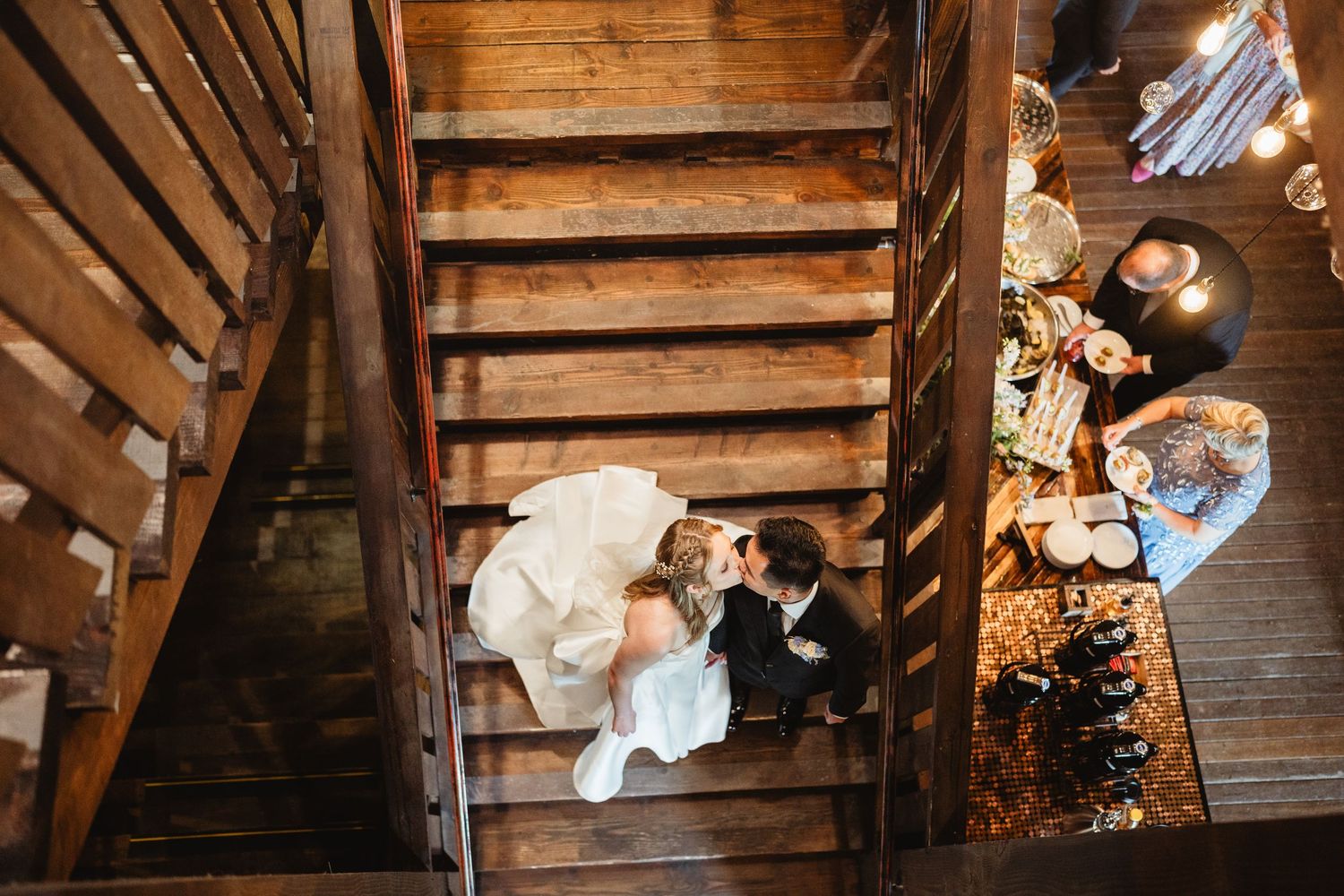 A couple sharing their wedding dance in a rustic wooden barn with exposed beams overhead and warm lighting.