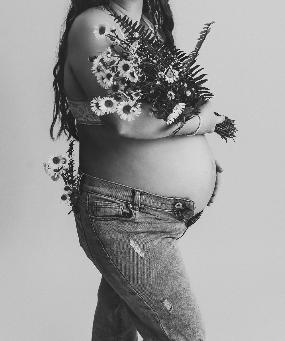 Artistic black and white maternity photo with floral elements.