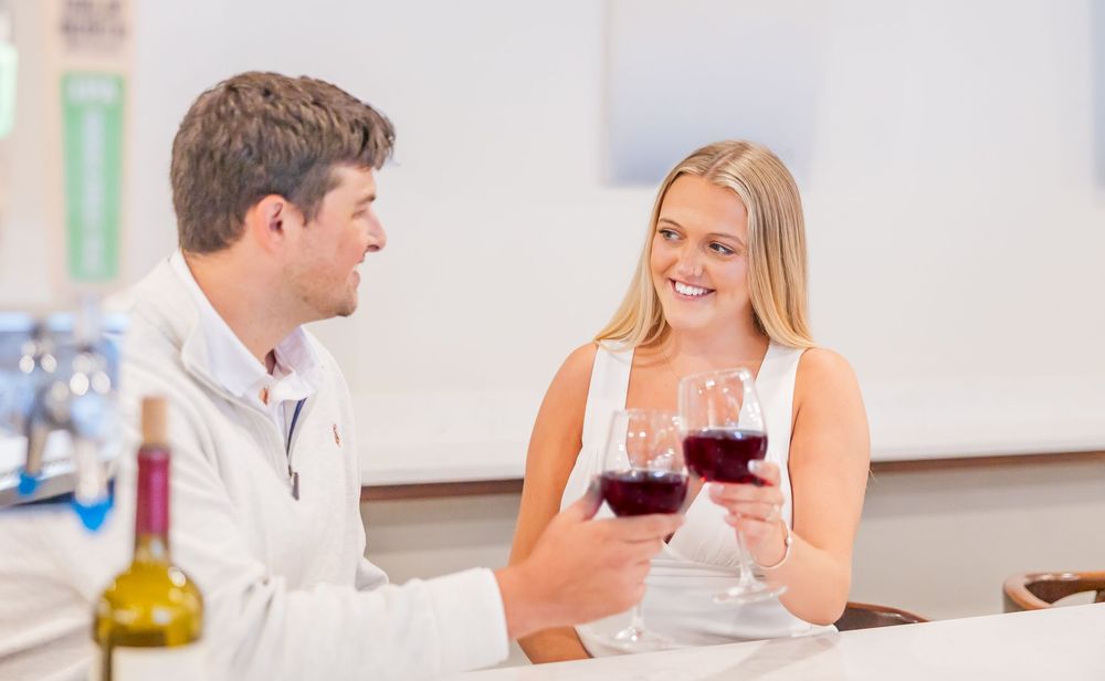 A couple enjoys wine together at a bright indoor bar counter.