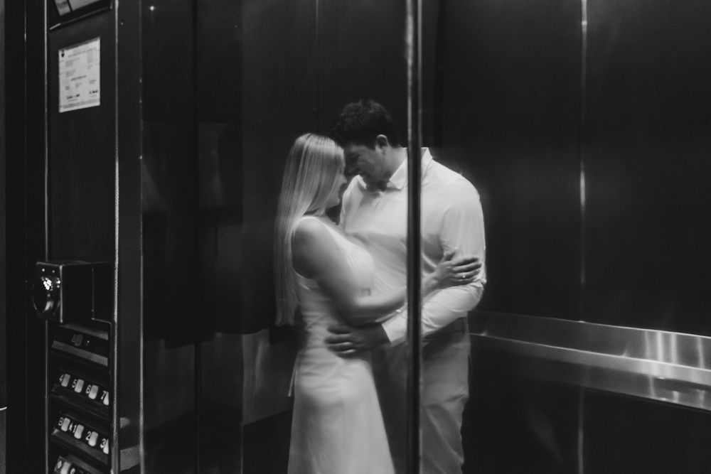 A romantic black and white photo of a couple embracing in an elevator.