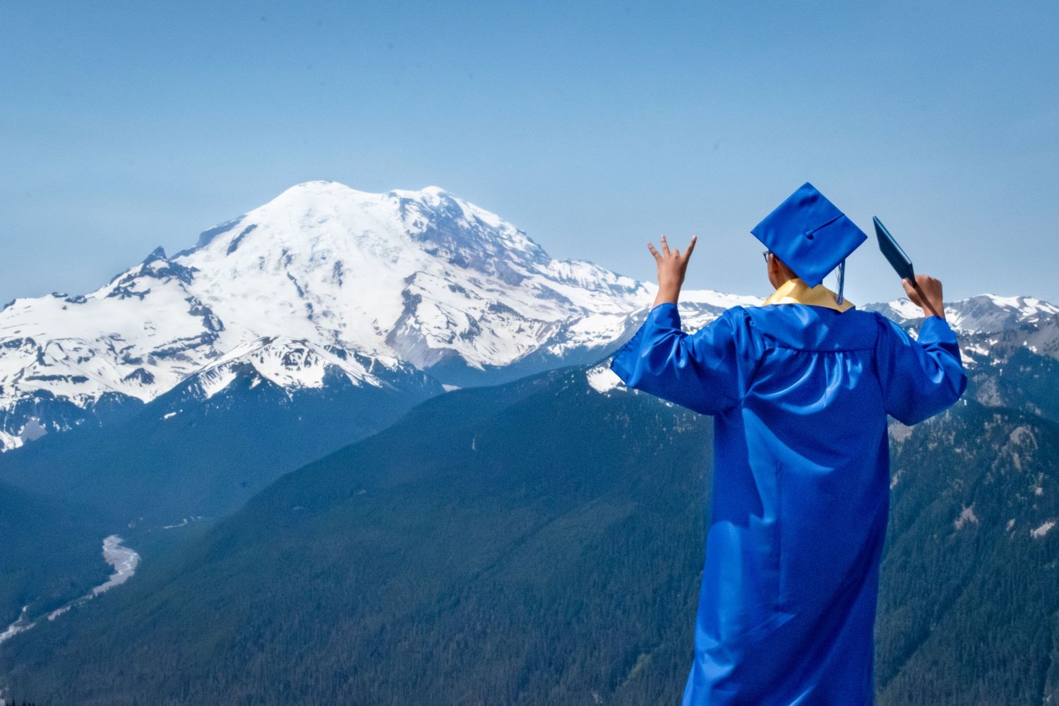 Playful graduation pose overlooking snow-capped peaks at Crystal Mountain senior session.