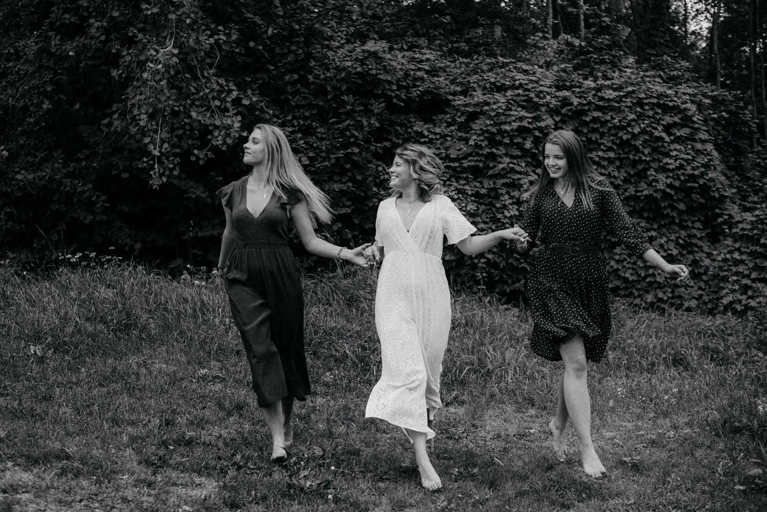 A group walks together through a shaded woodland path in casual attire.
