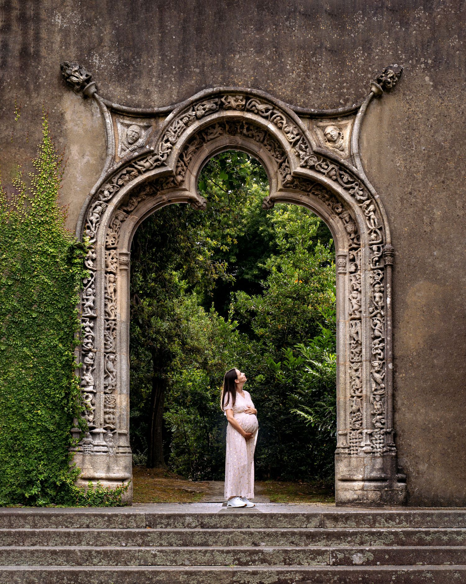 Sessão fotográfica de grávida no jardim, com pórtico muito bonito e antigo.