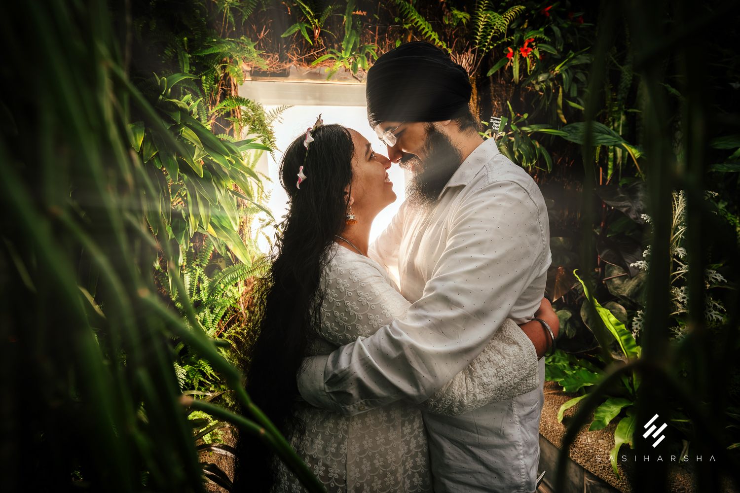 Romantic moment captured through tropical foliage in garden setting.