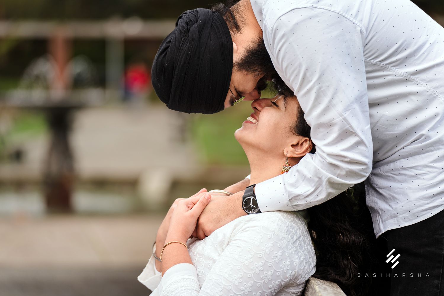 A tender romantic moment captured in white attire against a natural backdrop.