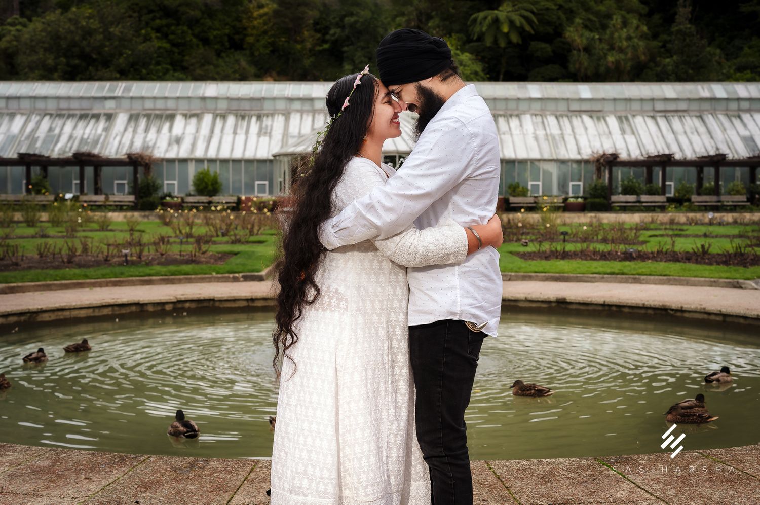 A romantic moment by a garden fountain with ducks swimming nearby.