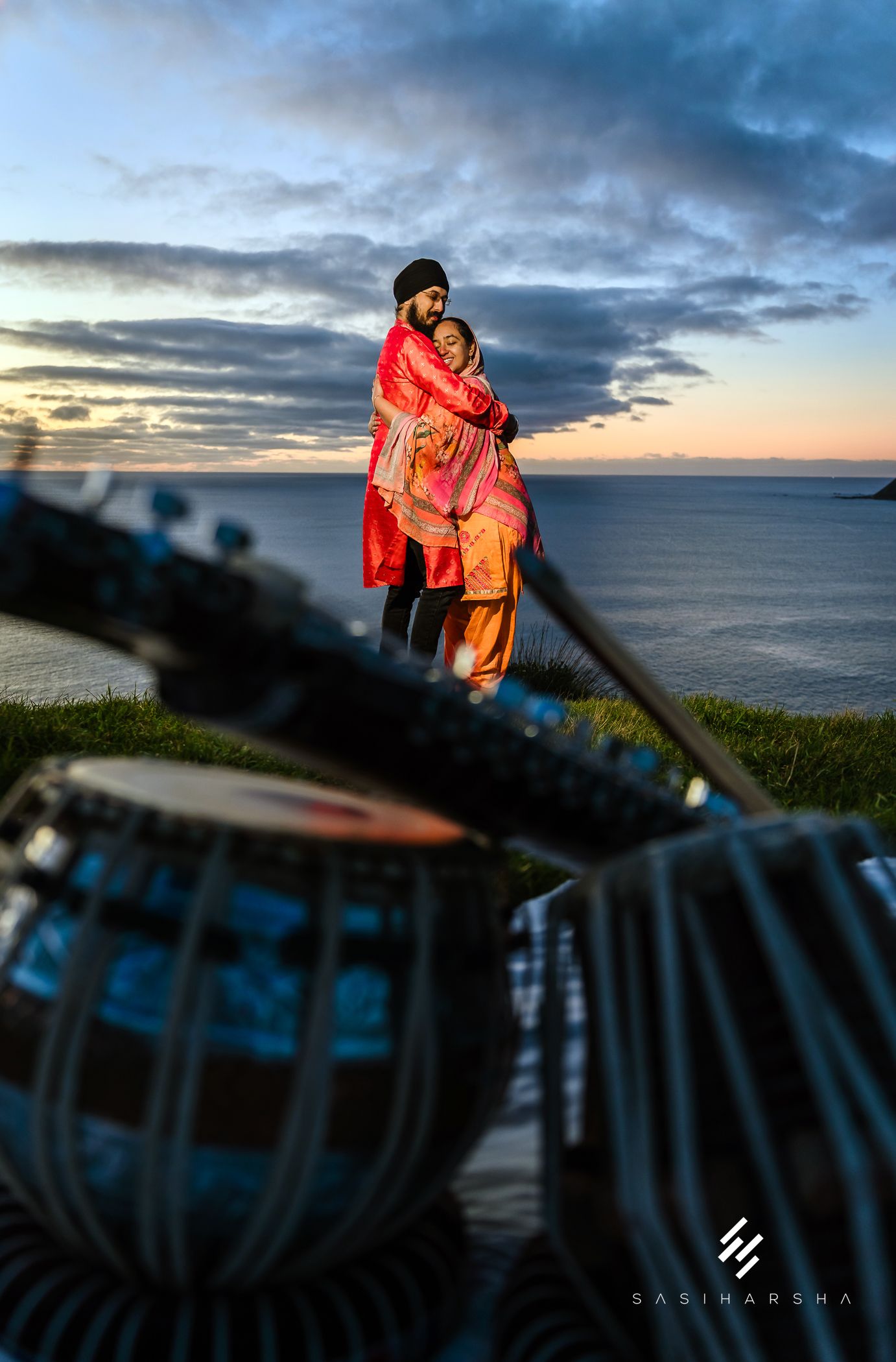 Traditional attire against sunset sky with musical instruments in foreground.