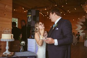 Newlyweds share their first bite of wedding cake together at their rustic reception.