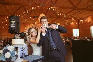 Wedding cake cutting ceremony in a rustic wooden barn with twinkle lights.