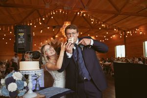 A couple enjoying their wedding cake during reception in a rustic venue with string lights.
