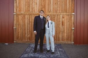 Couple stands together against a rustic wooden barn wall for a portrait.